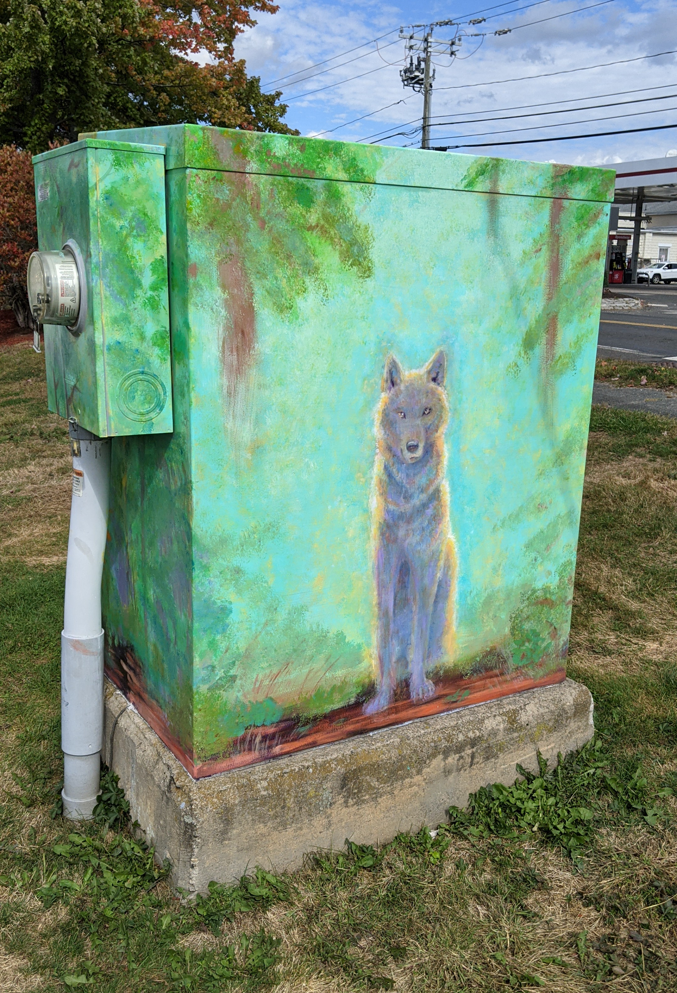 Finished electric box mural front with imprersiionistic wolf on a glowing blue background surrounded by woods.